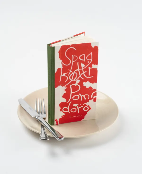 Ein rot-weiß-grünes Buch und Besteck auf einem Teller
